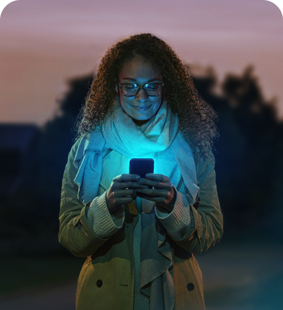 A woman gazing down at her smartphone screen, which emits a soft glow